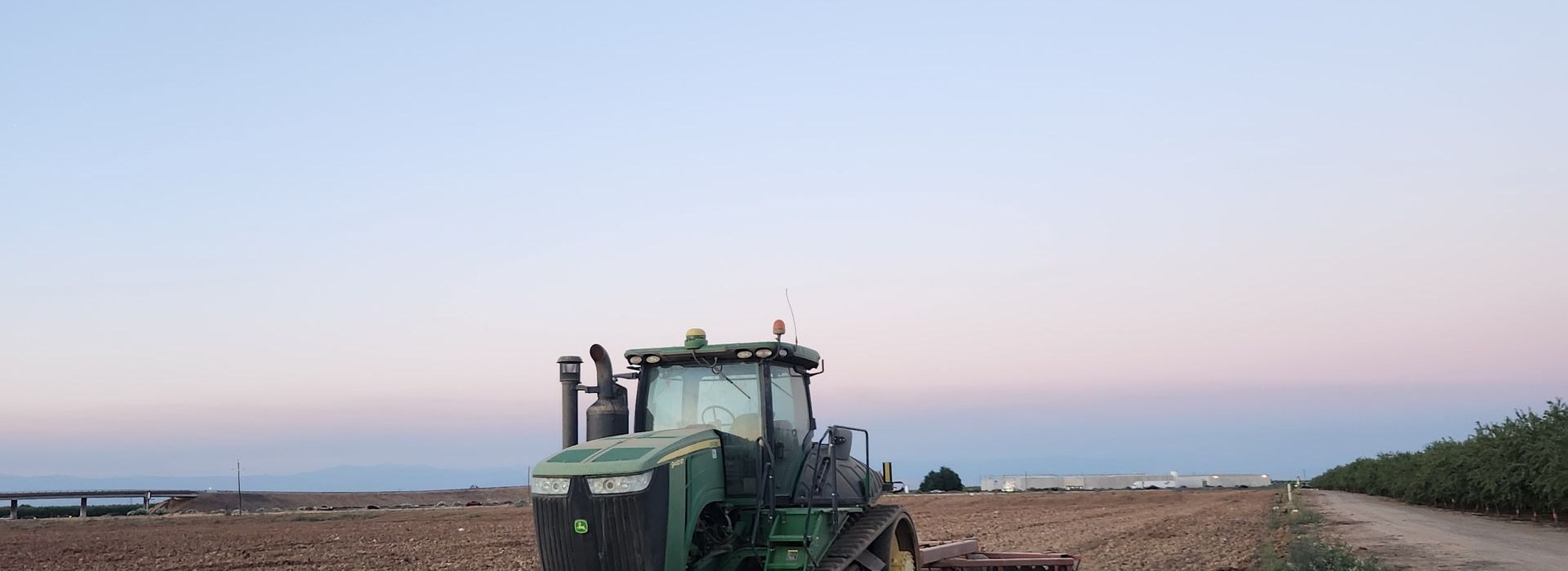 Modern tractor working in a Californian field at sunset